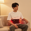 Person sitting while wearing the red light therapy waist belt